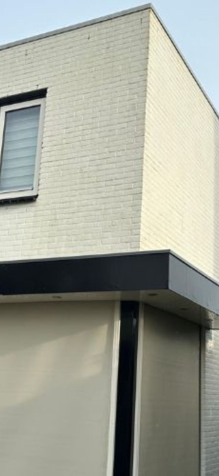 Modern, minimalistisch witgepleisterd hoekhuis met raam.