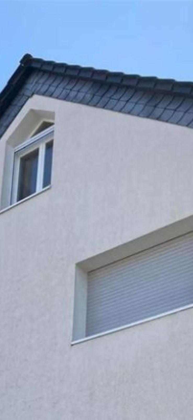 Modern huis met witte gevel en dakraam