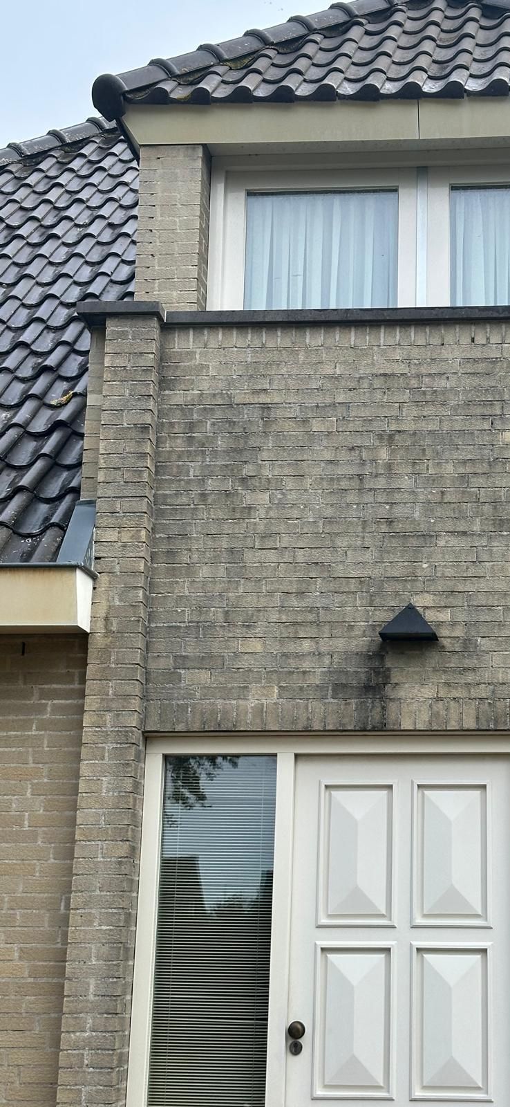 Bakstenen gevel met twee ramen en deur.