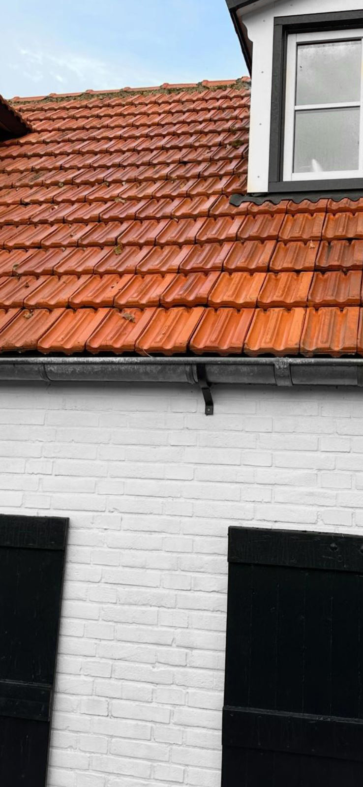 Rood dak met witte muur en zwarte luiken