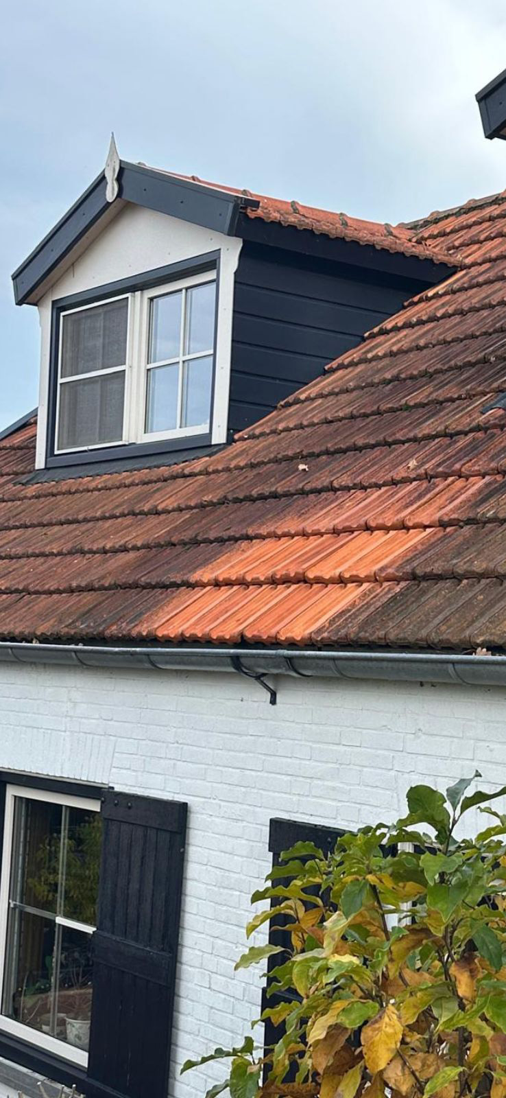 Dakraam met bakstenen schuin dak op wit huis